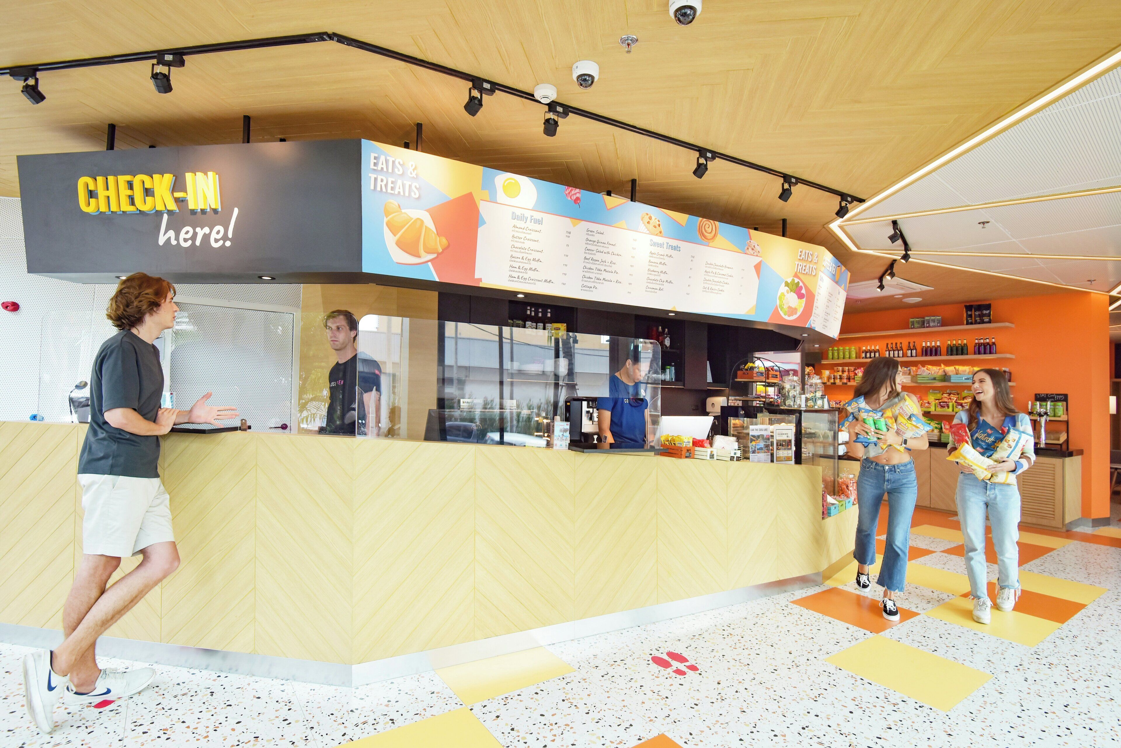 A food counter with a menu, a security camera, and a sign that says 'CHECK-IN here!'
