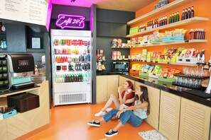 A brightly lit snack bar with a neon sign, a beverage dispenser, and shelves stocked with snacks and drinks. - COSI Krabi Ao Nang Beach (Krabi)