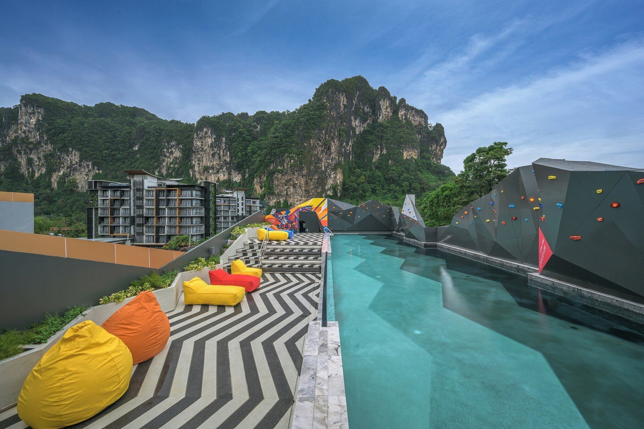 A swimming pool with a climbing wall and colorful seating.