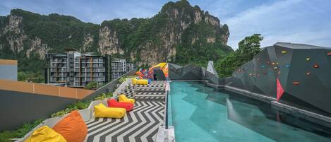 A swimming pool with a climbing wall and colorful seating.