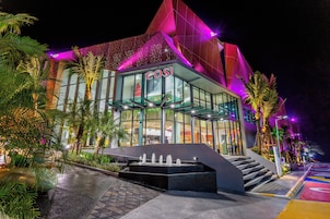 Un edificio moderno con fachada de vidrio, un llamativo letrero 'COSI' y un diseño de techo geométrico único.