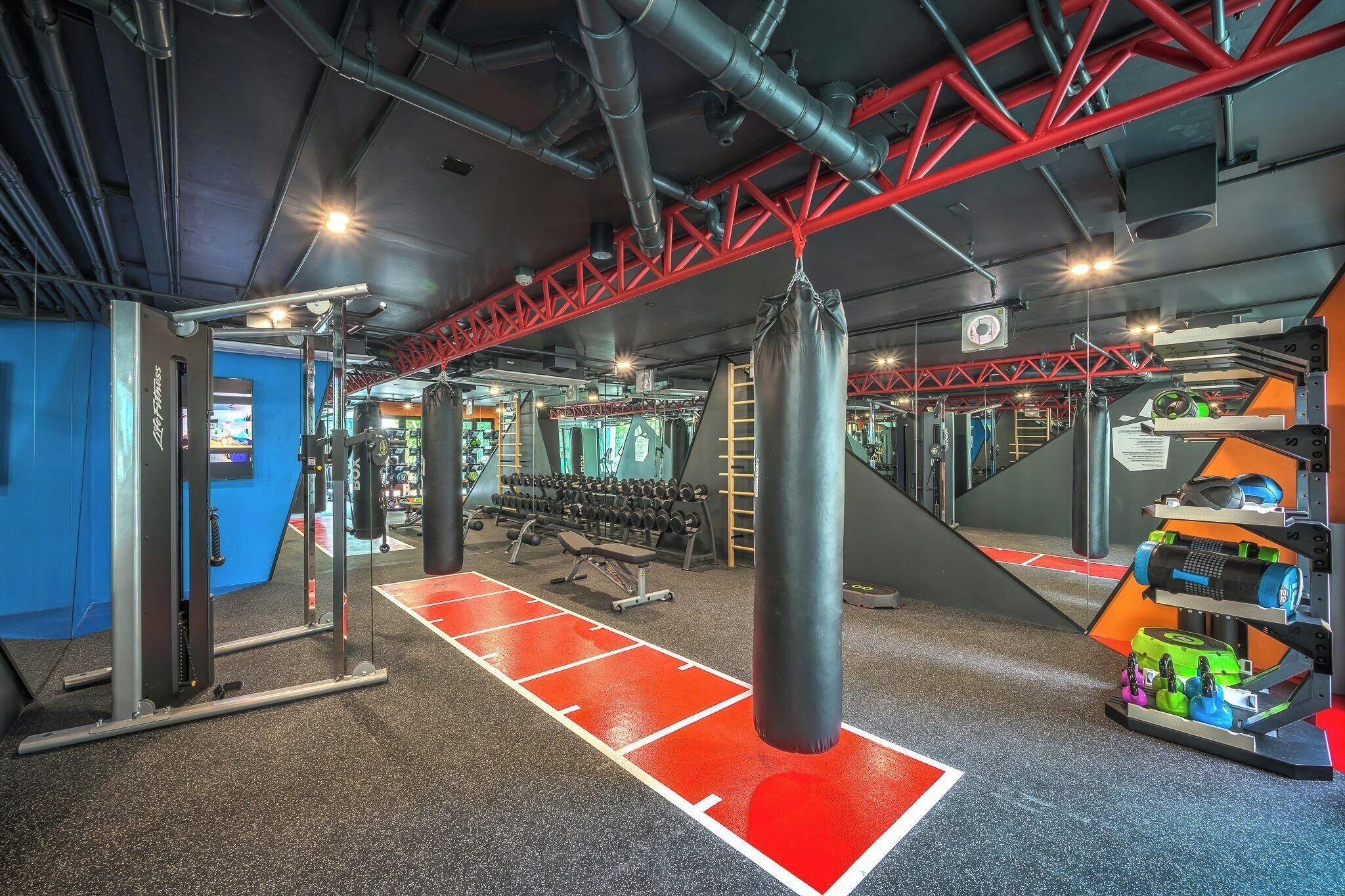 A gym with weightlifting equipment, a punching bag, and a red and black color scheme.