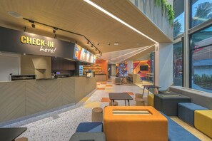 Ein modernes Café-Interieur mit Check-in-Schalter, Sitzbereich und einer farbenfrohen Wandmalerei.