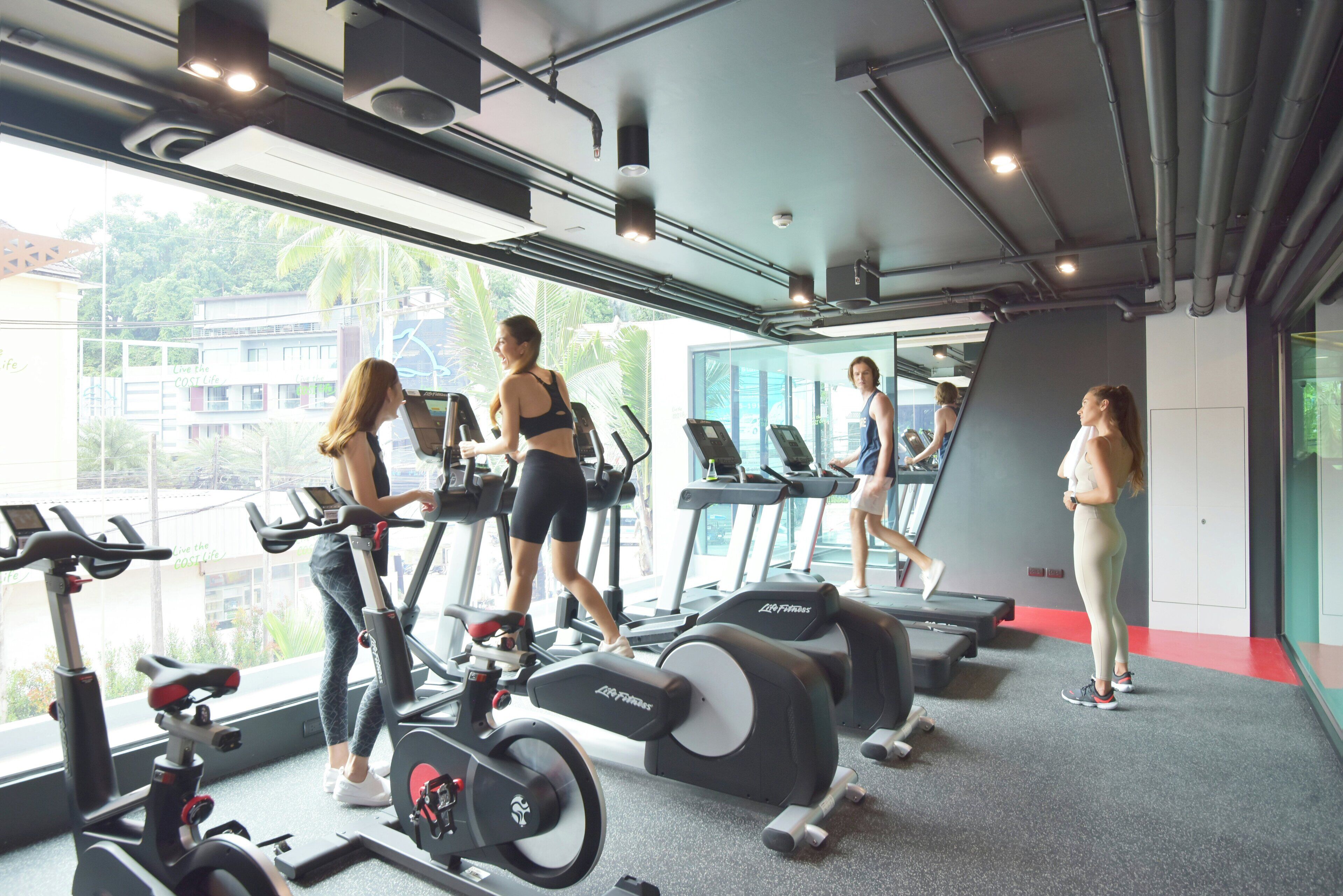 Un gimnasio con cintas de correr, bicicletas estáticas y un espejo grande.