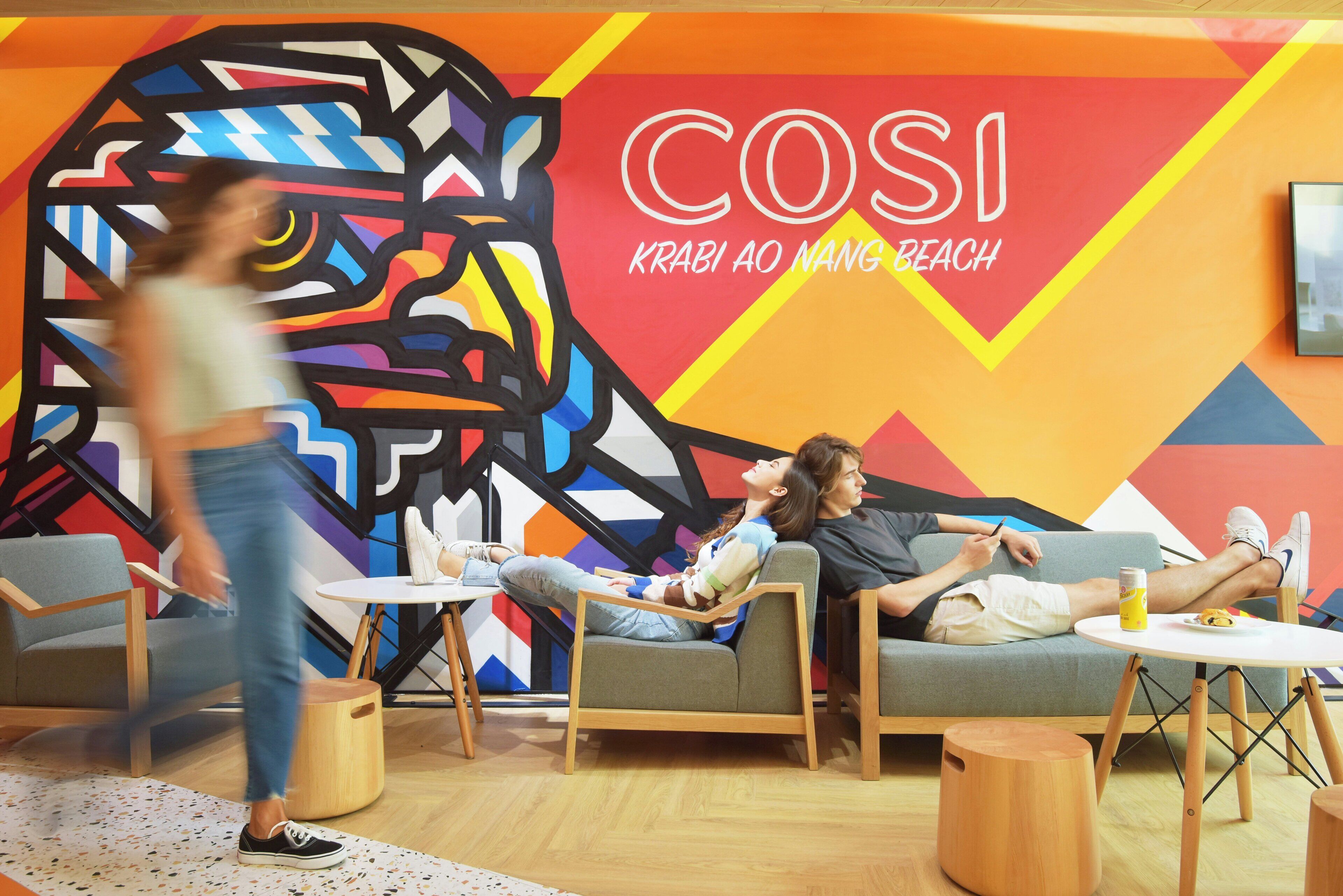 A modern lounge area with colorful wall art, comfortable seating, and a casual atmosphere.