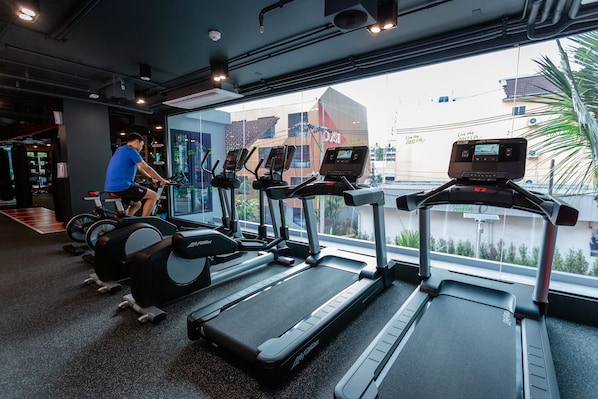 Ein Fitnessstudio mit Laufbändern, Ergometer und einer Person, die Fahrrad fährt.