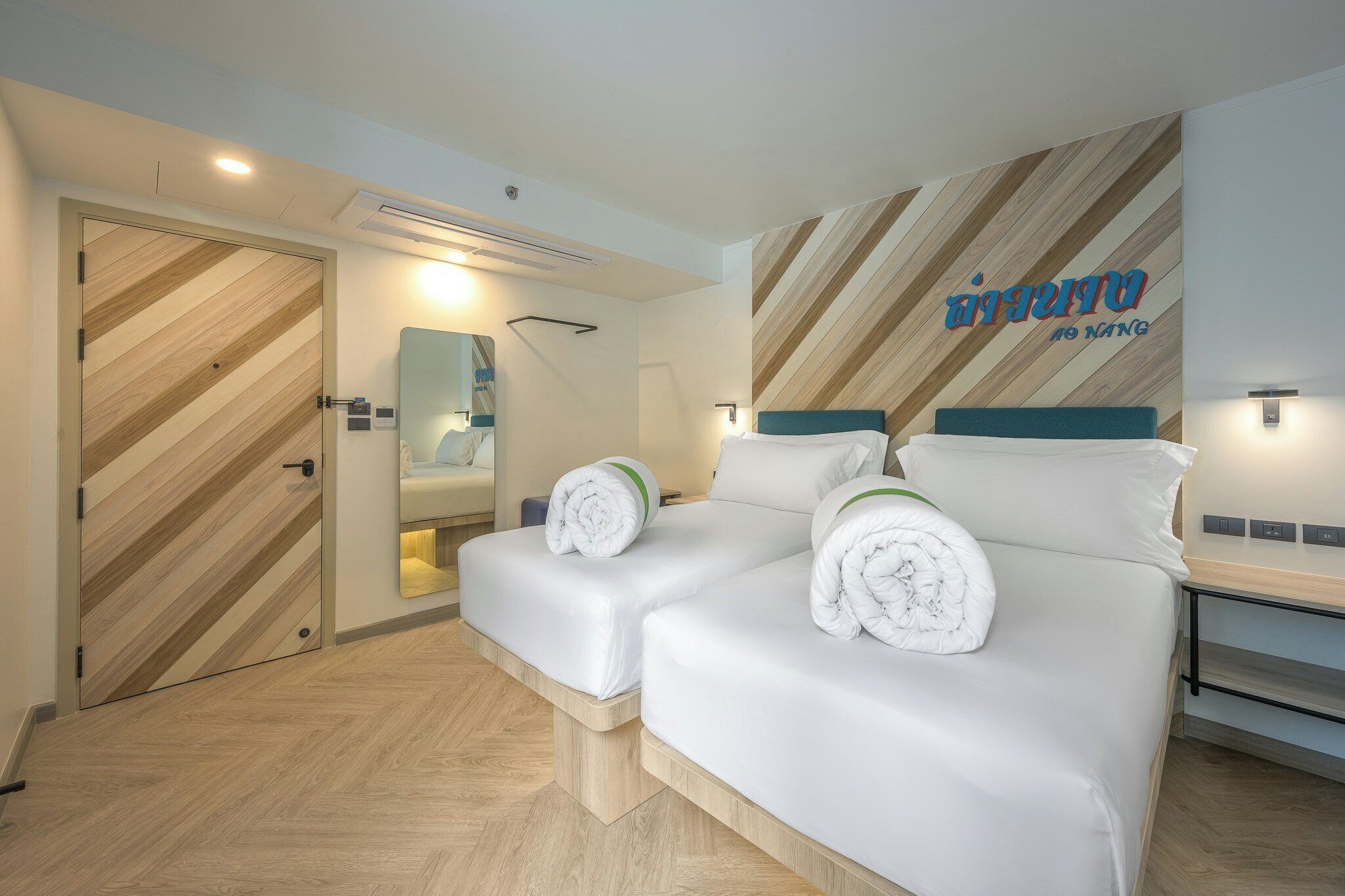 Una habitación de hotel con una cama, mesitas de noche, un espejo y una pared con diseño decorativo.