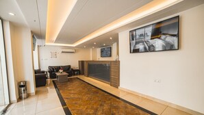 A modern hotel lobby with a seating area, a fireplace, and a large artwork on the wall. - Joar Beach Hotel (Aqaba)