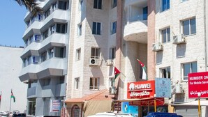 A multi-story hotel with balconies, a Huawei sign, and a flag. - Joar Beach Hotel (Aqaba)