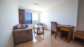 A hotel room with a sofa, a desk, and a view of the sea. - Joar Beach Hotel (Aqaba)