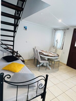 Un espace de vie compact comprenant un lit superposé, une table à manger avec des chaises et un escalier.