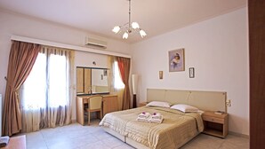 A hotel room with a bed, bedside table, nightstand, desk, chair, and a large window with curtains. - 3 Bedrooms Apartment included Car Rental (heated pool) (santorini)