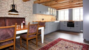 Una cocina con vigas de madera, pared de ladrillo y comedor con mesa y sillas.