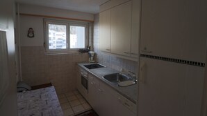 Eine kleine Küche mit weißen Schränken, einem Spülbecken und einem Fenster.