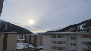 Ein mehrstöckiges Gebäude mit verschneiter Landschaft und Bergen im Hintergrund.