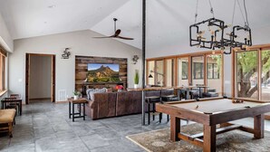 A spacious living area with a pool table, a sofa, and a television mounted on a wooden wall. - Relax & Play -Ultimate Retreat- Pickleball & more! (Scottsdale)