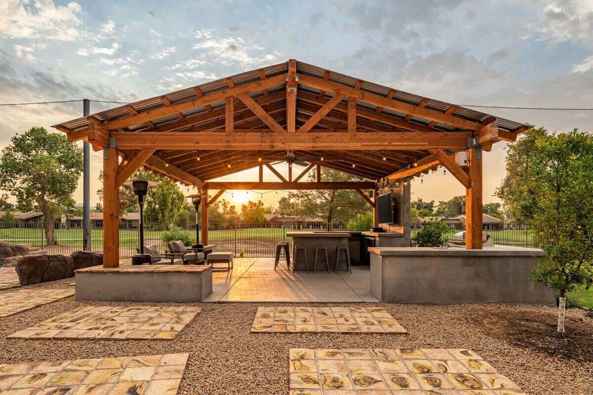 Un patio techado al aire libre con techo de madera, zona de estar y barra.