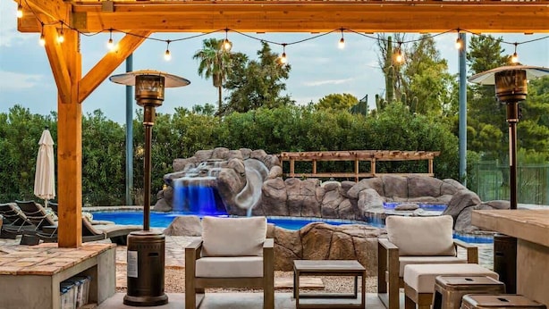 A pool area with a waterfall feature, outdoor seating, and string lights. - Relax & Play -Ultimate Retreat- Pickleball & more! (Scottsdale)