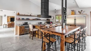 A modern kitchen with a central island, built-in appliances, and a large dining area with wooden tables and chairs. - Relax & Play -Ultimate Retreat- Pickleball & more! (Scottsdale)