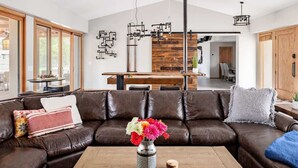 A modern living room with a brown leather sofa, a wooden coffee table, and a vase of flowers. - Relax & Play -Ultimate Retreat- Pickleball & more! (Scottsdale)