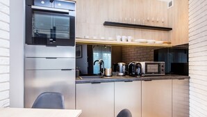 Une cuisine compacte équipée d’un four, d’un micro-ondes et d’une machine à café intégrés.