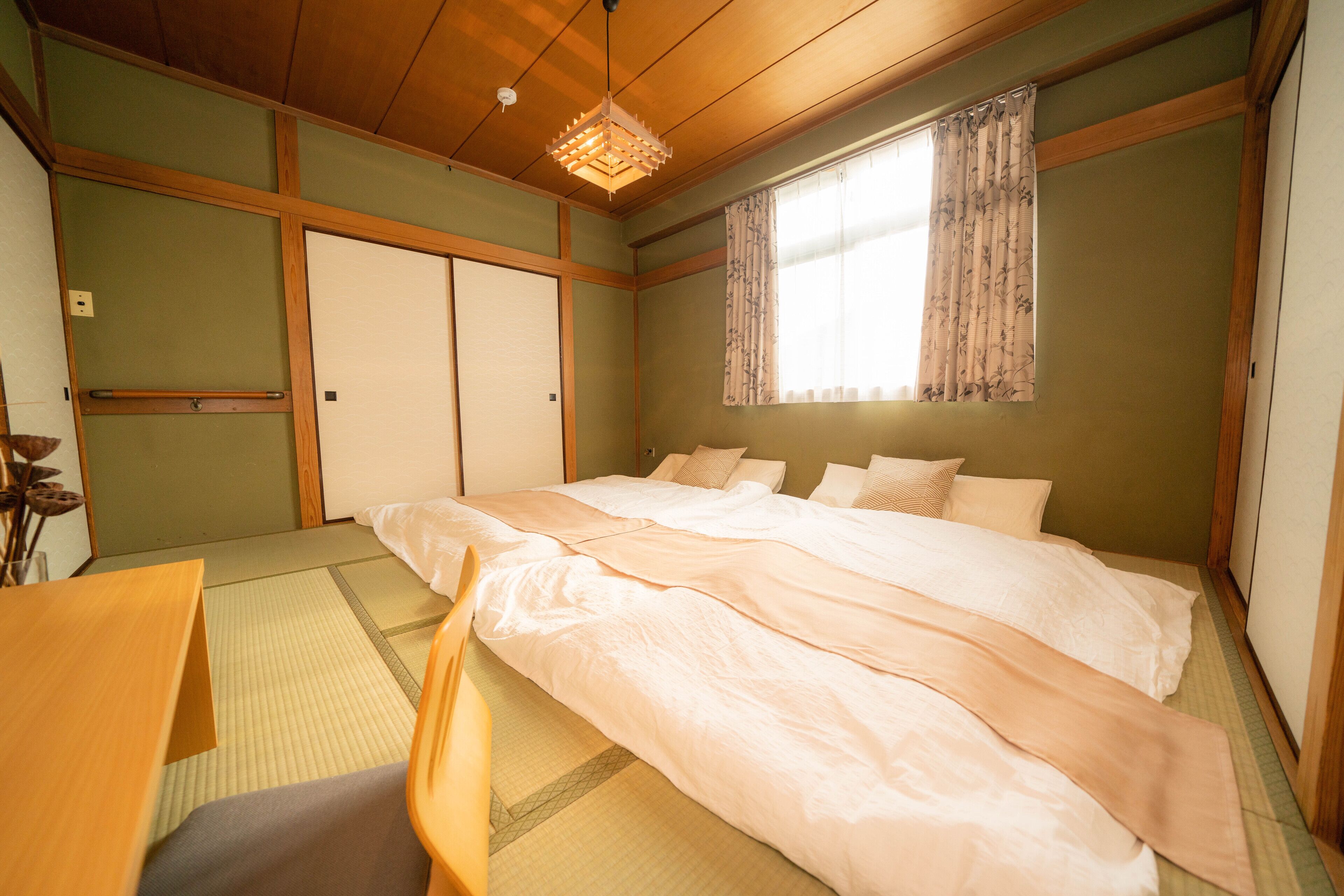 Une chambre de style japonais traditionnel, avec un sol recouvert de tatamis, un lit bas en bois et un paravent shoji.