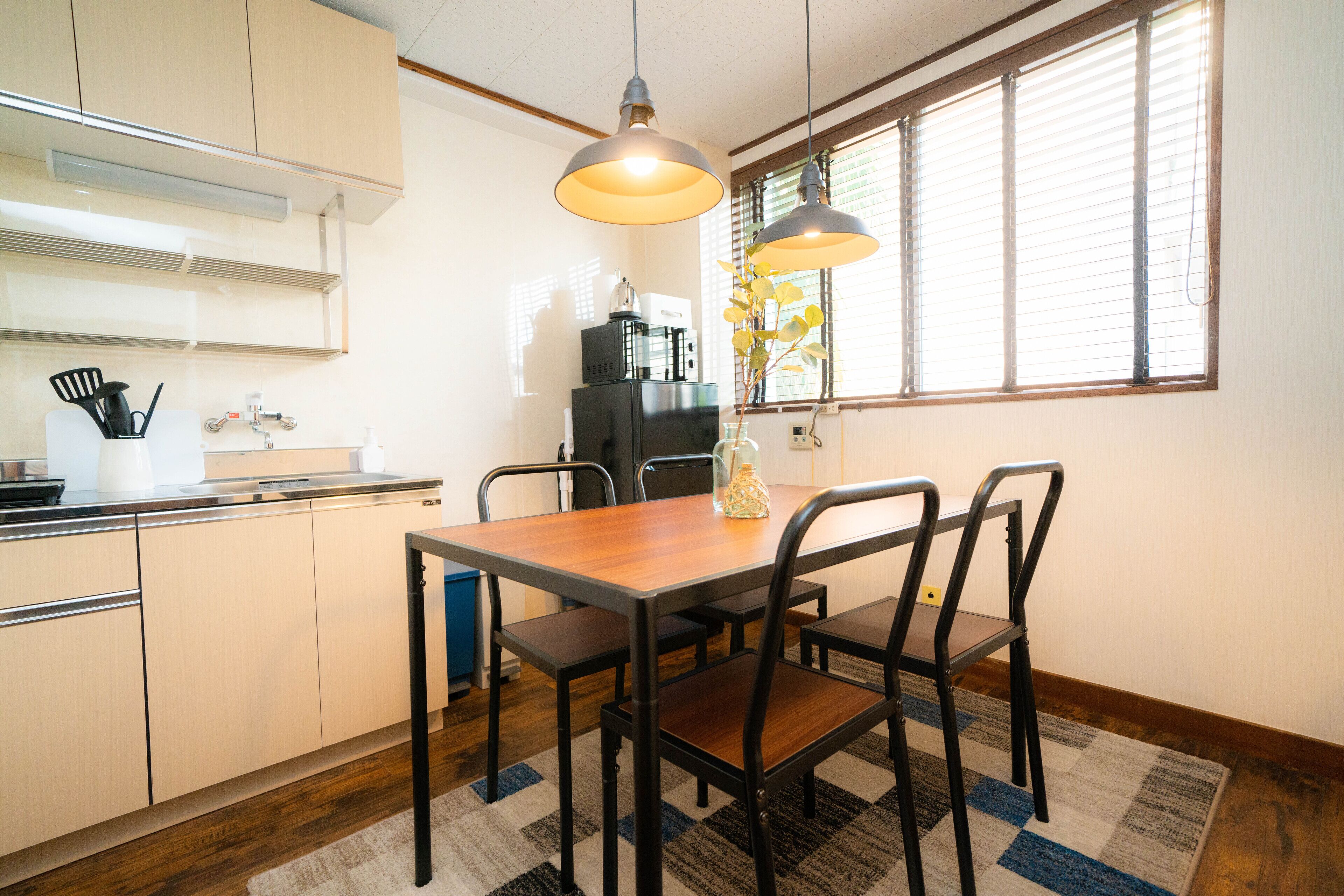 A kitchen with a dining table, chairs, and a window with blinds.