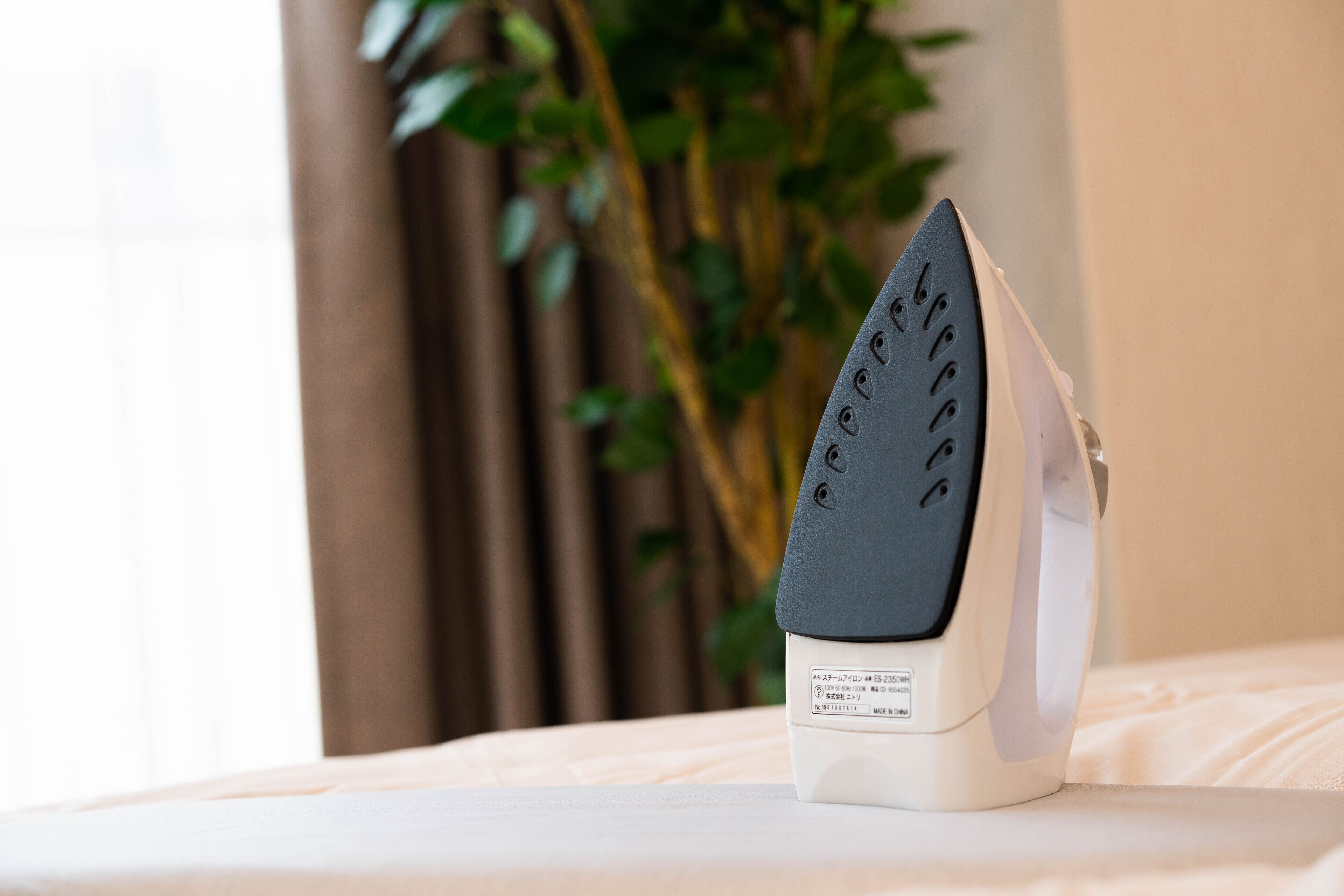 A modern iron with a digital display on a bed.