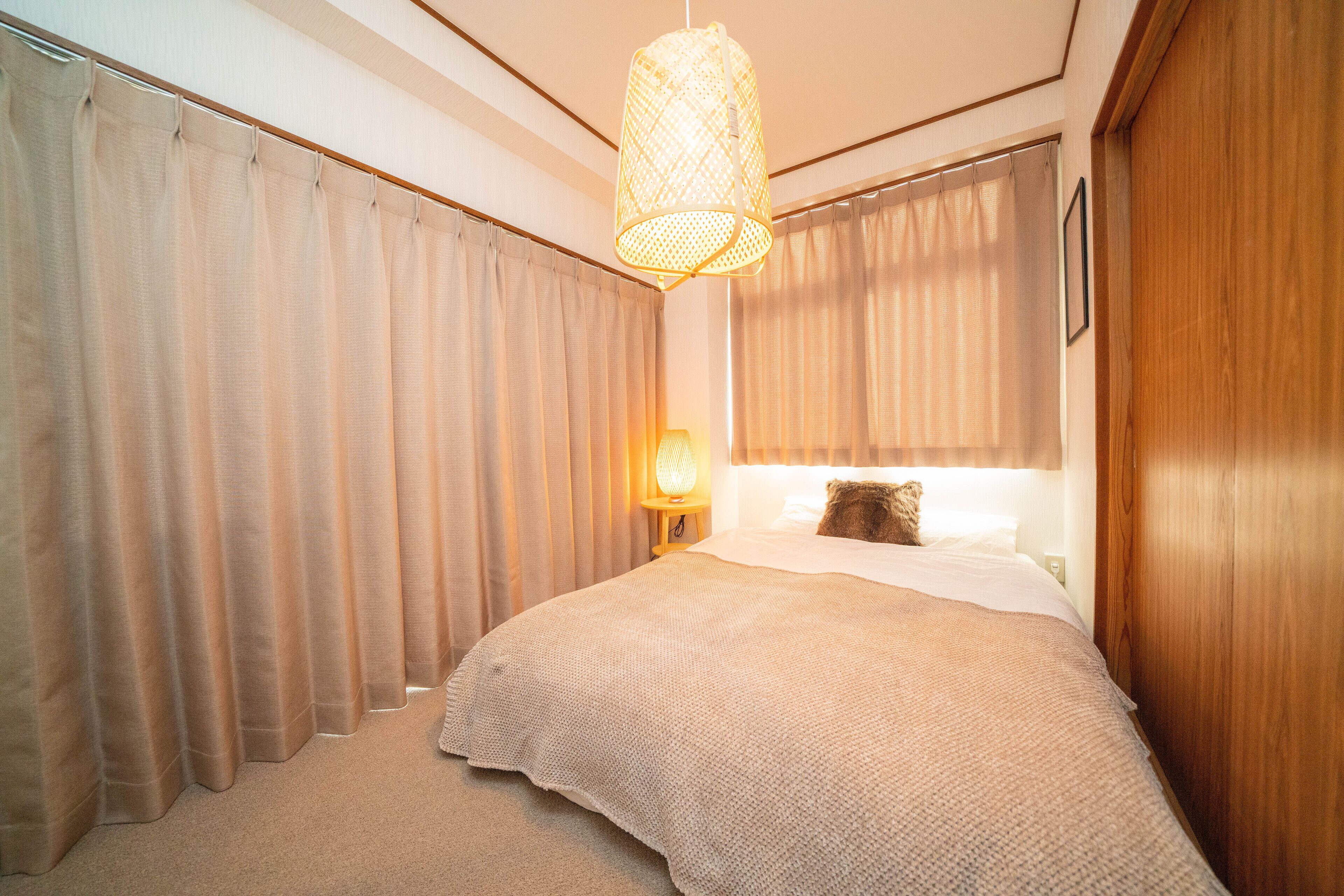 Ein Schlafzimmer mit einem großen Bett, einer Hängeleuchte und Vorhängen.