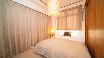 Ein Schlafzimmer mit einem großen Bett, einer Hängeleuchte und Vorhängen.