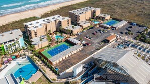 An aerial view of a coastal hotel with multiple buildings, a beach, and a pool area.