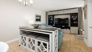 A modern kitchen with a dining area, a TV, and a large window.