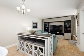 A modern kitchen with a dining area, a TV, and a large window. - Sea Vista I #111 | Beachfront Ground-Floor Condo • Direct Beach Access • Two Community Pools (South Padre Island)