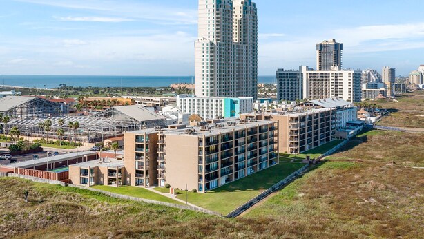 A high-rise hotel with multiple floors, a rooftop pool, and a view of the ocean.