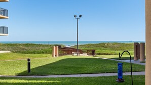 A grassy area with a pathway, a blue decorative object, and a view of the ocean.