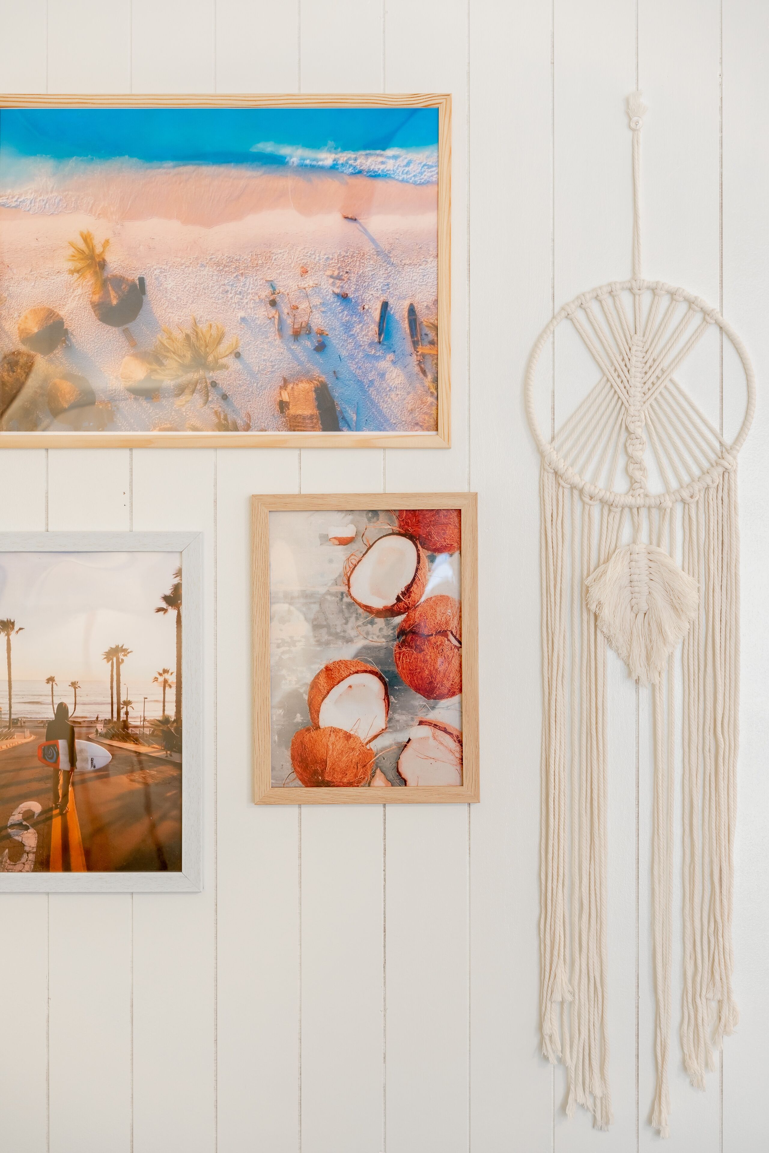 Un mur orné de trois œuvres d’art encadrées et d’une décoration murale en macramé.