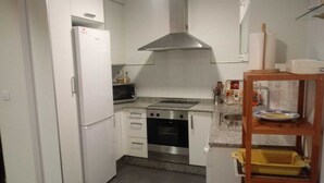 A compact kitchen with white cabinets, a stainless steel range hood, a microwave, and a built-in oven.