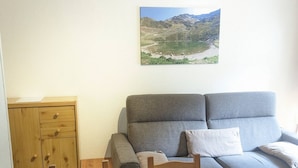 A living room with a grey sofa, a wooden cabinet, and a table. - 2-room cabin apartment at the foot of the slopes (Les Adrets-Prapoutel)