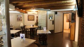 Een restaurant met houten balken in het plafond, tafels, stoelen en een bar.