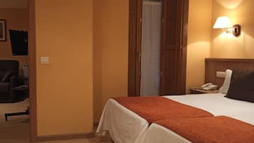 A hotel room with a bed, a nightstand, a phone, and a wall-mounted lamp.
