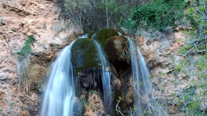 A natural waterfall cascading over rocks in a forested area.