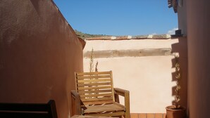 A wooden chair and table on a tiled patio with a potted plant.