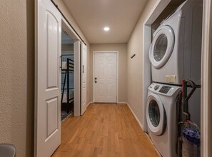 Ein Waschraum mit Waschmaschine, Trockner und einer Tür zu einer Treppe.