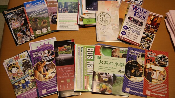 Een verzameling reisbrochures en gidsen op een tafel.
