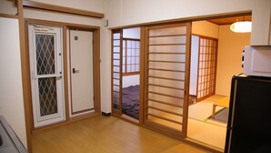 Une pièce de style japonais traditionnel, avec un sol recouvert de tatamis, une porte coulissante, un lit avec un futon et une petite table.