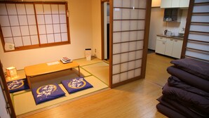 Une pièce de style japonais traditionnel, avec un sol recouvert de tatamis, une petite table en bois et un futon servant de lit.