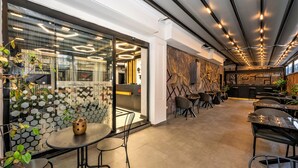 A modern interior with hexagonal patterned walls, a central seating area with a round table, and a long counter with chairs. - Confores Hotel (Istanbul)