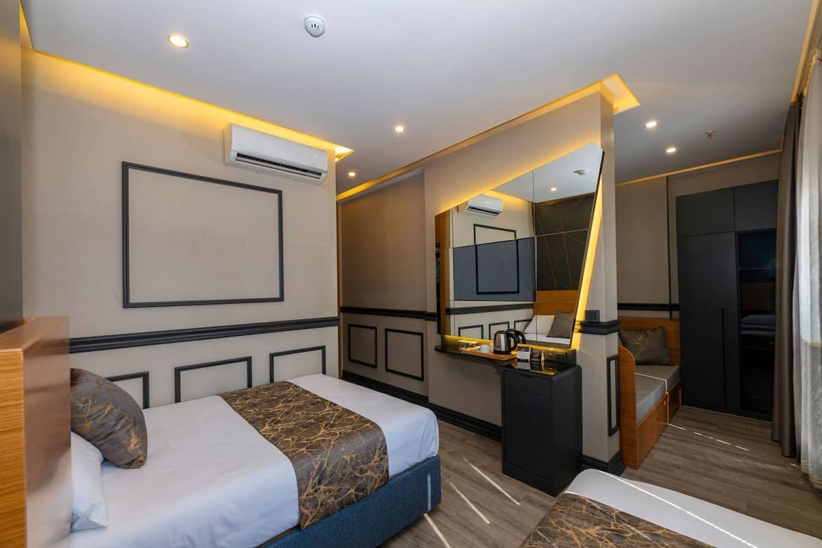 A hotel room with a bed, bedside table, mirror, wardrobe, and a small seating area.