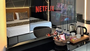 A hotel room with a large mirror reflecting the bed and a TV screen displaying the Netflix logo. - Confores Hotel (Istanbul)