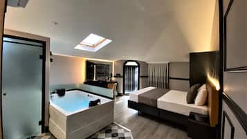 Una habitación de hotel moderna con tragaluz, baño independiente, bañera grande y cama con mesita de noche.